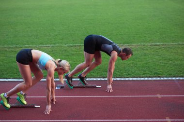 Athlete woman and man  running on athletics race track