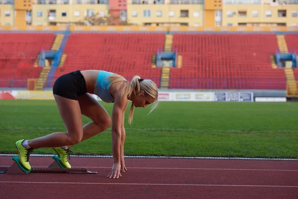 Mulher sprinter deixando blocos de partida — Fotografia de Stock