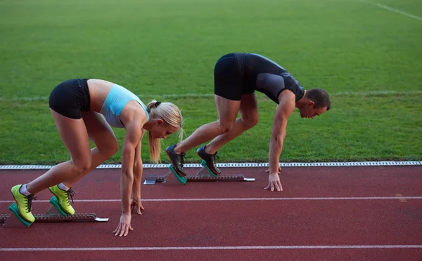 Athlète femme et homme courir sur piste de course d'athlétisme — Photo