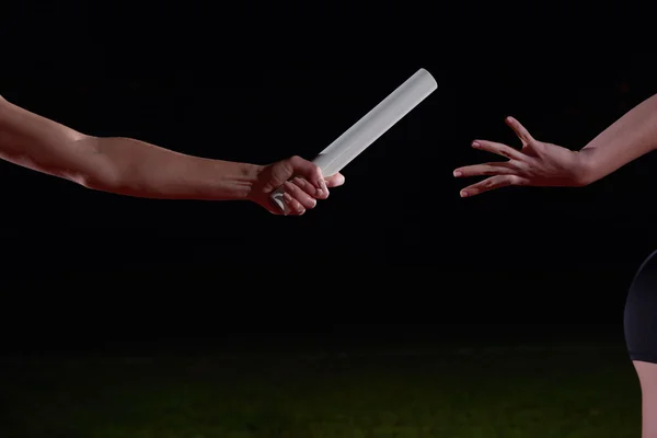 Athletic runners passing baton in relay race — Stock Photo, Image