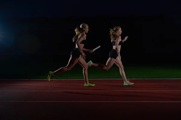 Atléticos corredores passando bastão na corrida de revezamento — Fotografia de Stock