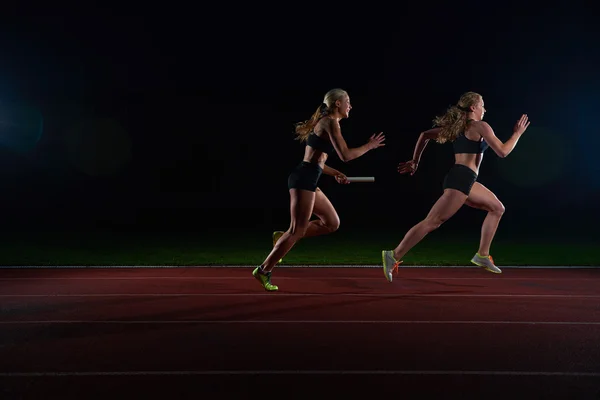 Atléticos corredores passando bastão na corrida de revezamento — Fotografia de Stock