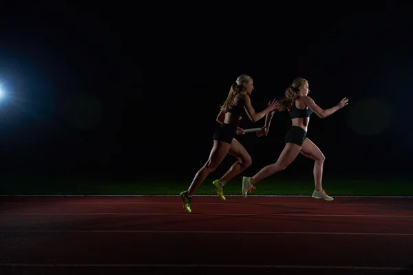 Urheilullinen juoksijat kulkee viestikapula rele kilpailussa — kuvapankkivalokuva