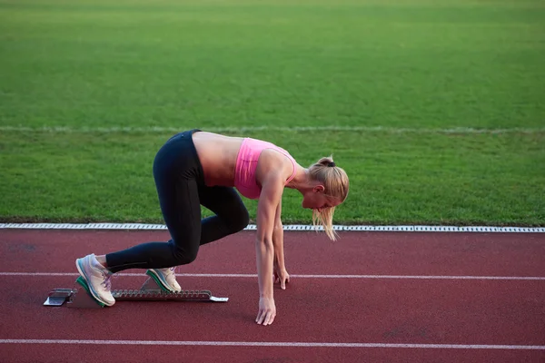 Mulher sprinter deixando blocos de partida — Fotografia de Stock