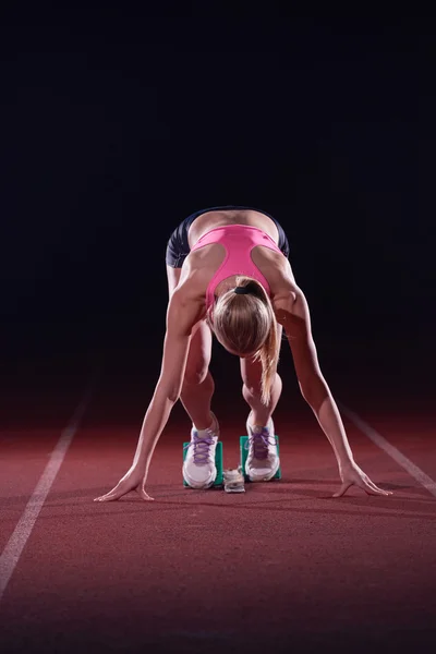 Woman  sprinter leaving starting blocks — Stock Photo, Image