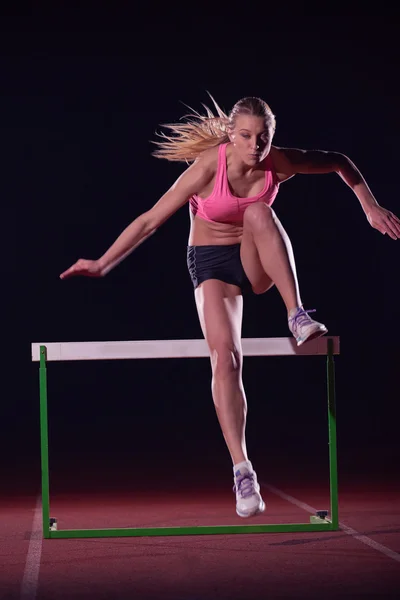 Atlet žena skákat přes překážky, — Stock fotografie