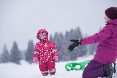 mom and cute little girl have fun in winter clipart