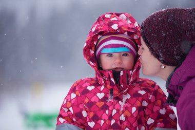 mom and cute little girl have fun in winter clipart