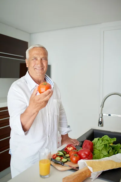 Man cooking at home preparing salad in kitchen — Stock Photo, Image