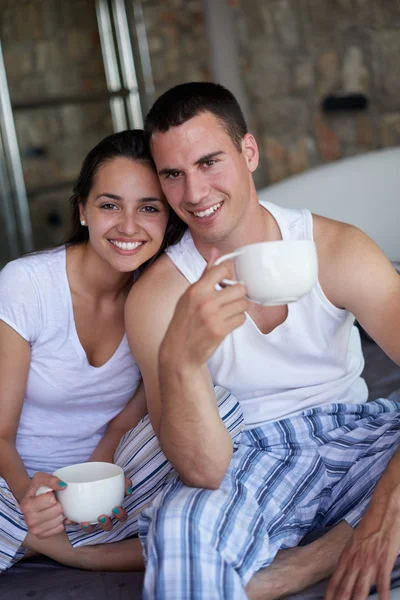 Çift rahatla ve yatakta kahve içmek — Stok fotoğraf