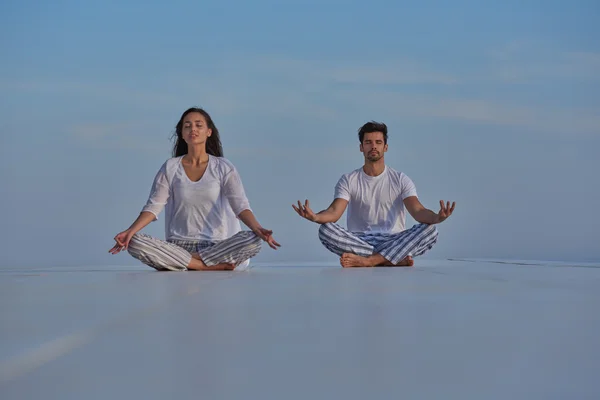 Jeune couple pratiquant le yoga — Photo