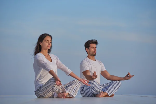 Jeune couple pratiquant le yoga — Photo