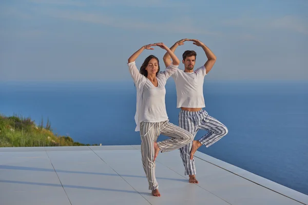 Jovem casal praticando ioga — Fotografia de Stock