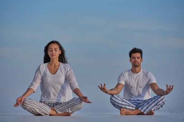 Jeune couple pratiquant le yoga — Photo