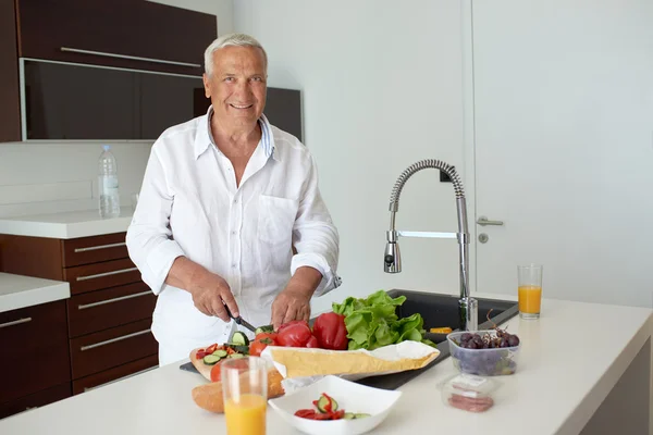 Man cooking at home preparing salad in kitchen — Stock Photo, Image