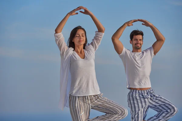 Jovem casal praticando ioga em casa terraço — Fotografia de Stock