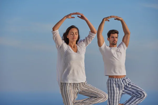 Jeune couple pratiquant le yoga — Photo