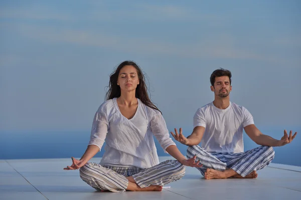 Jeune couple pratiquant le yoga — Photo