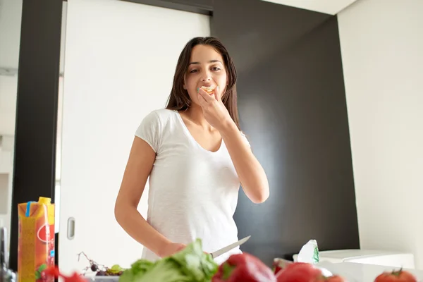 Genç bir kadın mutfakta yemek pişiriyor. — Stok fotoğraf