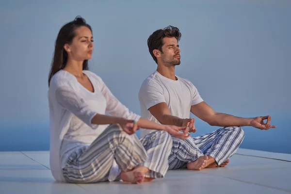 Jeune couple pratiquant le yoga — Photo