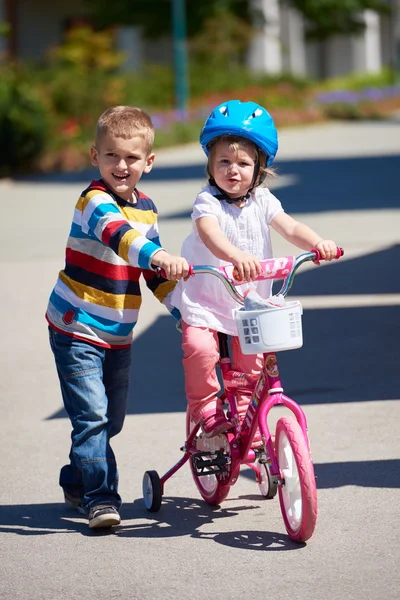 Boy and girl in park learning to ride a bike — Stock Photo, Image
