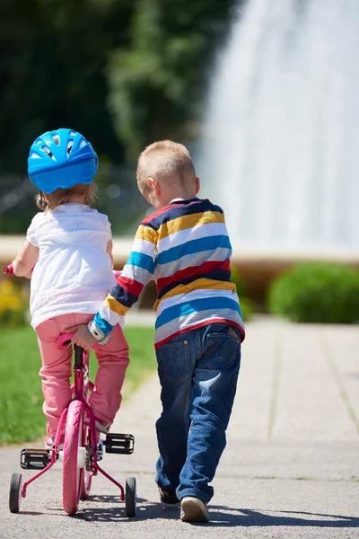 Niño y niña en el parque aprendiendo a andar en bicicleta —  Fotos de Stock