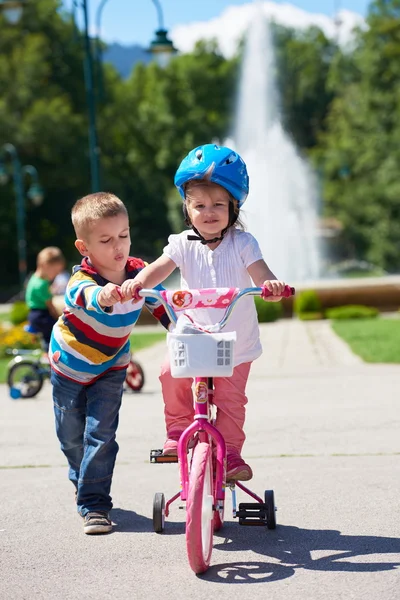Poika ja tyttö puistossa oppiminen ratsastaa pyörä — kuvapankkivalokuva
