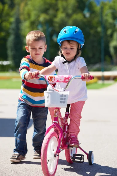 Niño y niña en el parque aprendiendo a andar en bicicleta — Foto de Stock