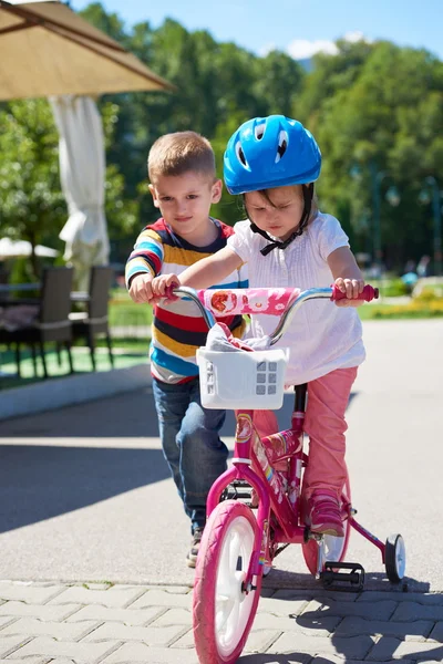 Niño y niña en el parque aprendiendo a andar en bicicleta —  Fotos de Stock