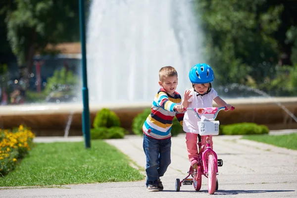 Αγόρι και κορίτσι σε πάρκο Μαθαίνοντας να οδηγήσω ένα ποδήλατο — Φωτογραφία Αρχείου