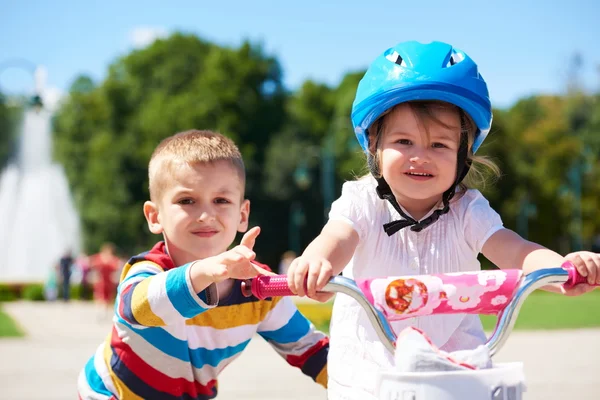 Menino e menina no parque aprendendo a andar de bicicleta — Fotografia de Stock