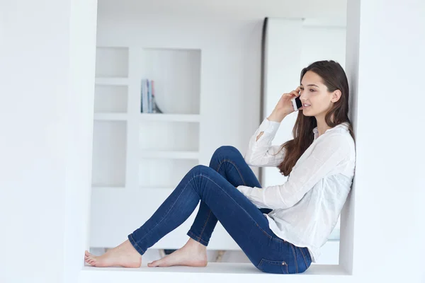 Mulher jovem usando celular em casa — Fotografia de Stock