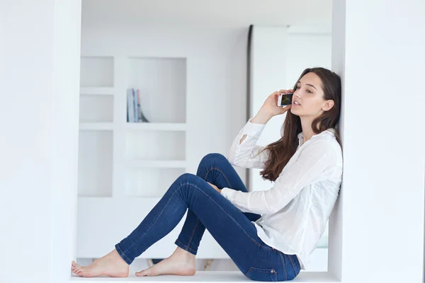 Jeune femme utilisant un téléphone portable à la maison — Photo