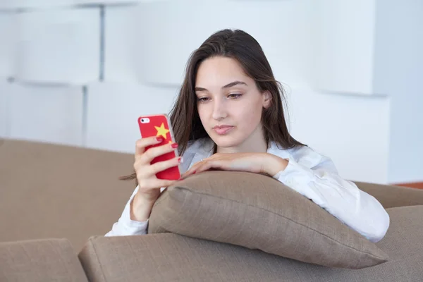 Jonge vrouw met behulp van mobiele telefoon thuis — Stockfoto