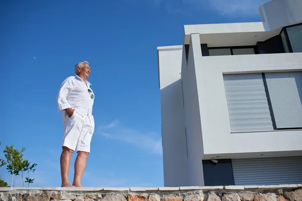 Hombre mayor frente a la casa moderna — Foto de Stock