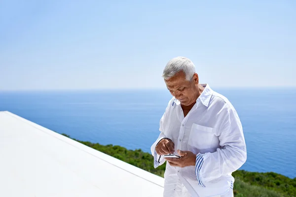 Старший чоловік використовує смартфон — стокове фото