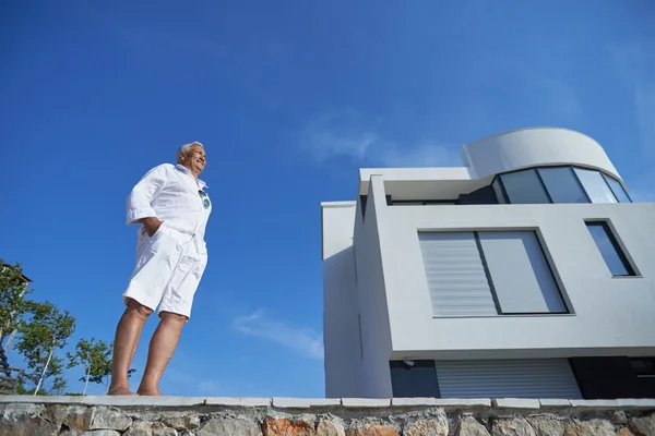 Senior man in front of modern home — Stock Photo, Image