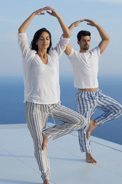 Jovem casal praticando ioga — Fotografia de Stock