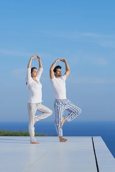 Jeune couple pratiquant le yoga — Photo
