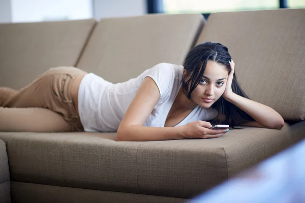 Jonge vrouw met behulp van mobiele telefoon thuis — Stockfoto