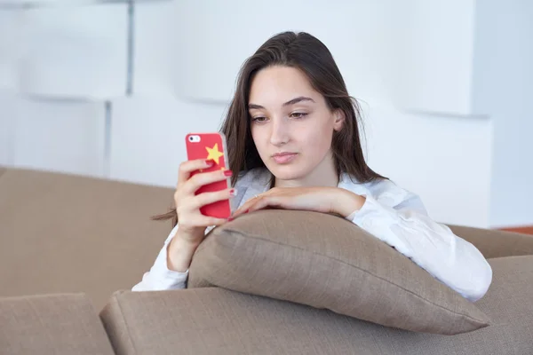 Jonge vrouw met behulp van mobiele telefoon thuis — Stockfoto