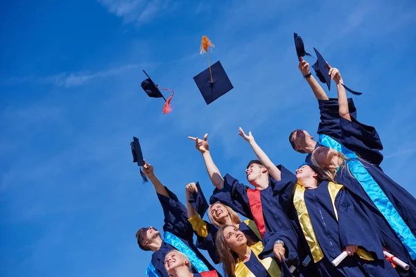 Middelbare school afgestudeerden gooien van hoeden — Stockfoto