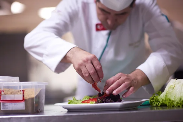 Chef in kitchen preparing and decorating food — Stock Photo, Image