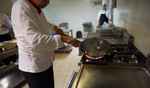 Шеф-повар на кухне готовит еду с огнем — стоковое фото
