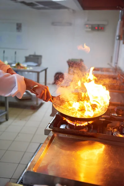 Chef dans la cuisine de l'hôtel préparer la nourriture avec le feu — Photo