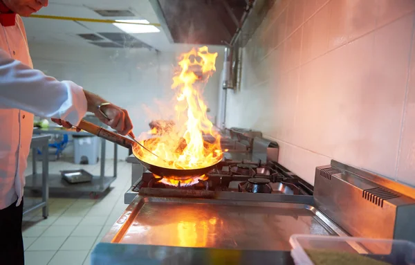 Chef en la cocina preparar la comida con fuego — Foto de Stock