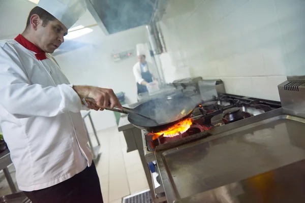 Koch in Küche bereitet Essen mit Feuer zu — Stockfoto