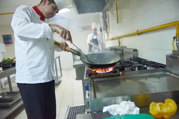 Koch in Küche bereitet Essen mit Feuer zu — Stockfoto