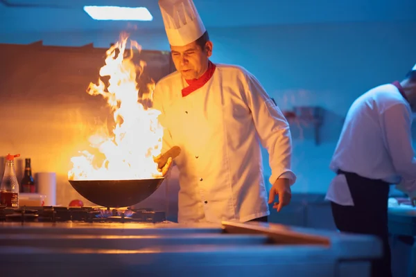 Koch in Küche bereitet Essen mit Feuer zu — Stockfoto