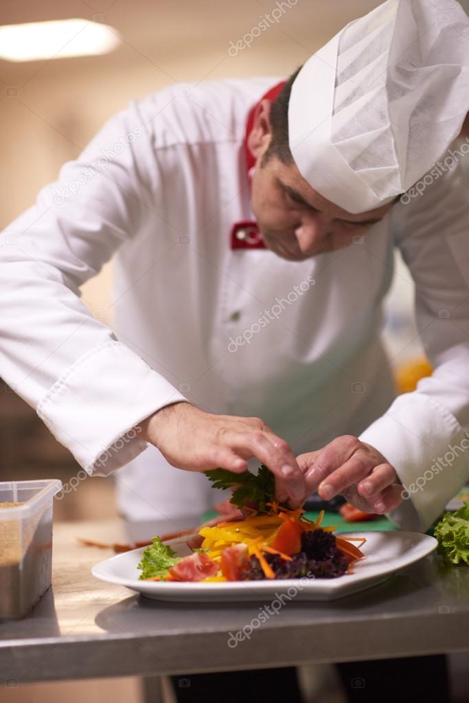 chef in kitchen preparing and decorating food